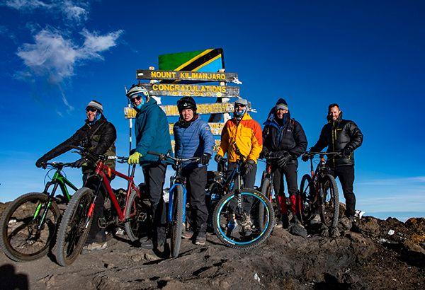 People standing at the top of mountain kilimanjaro with bikes
